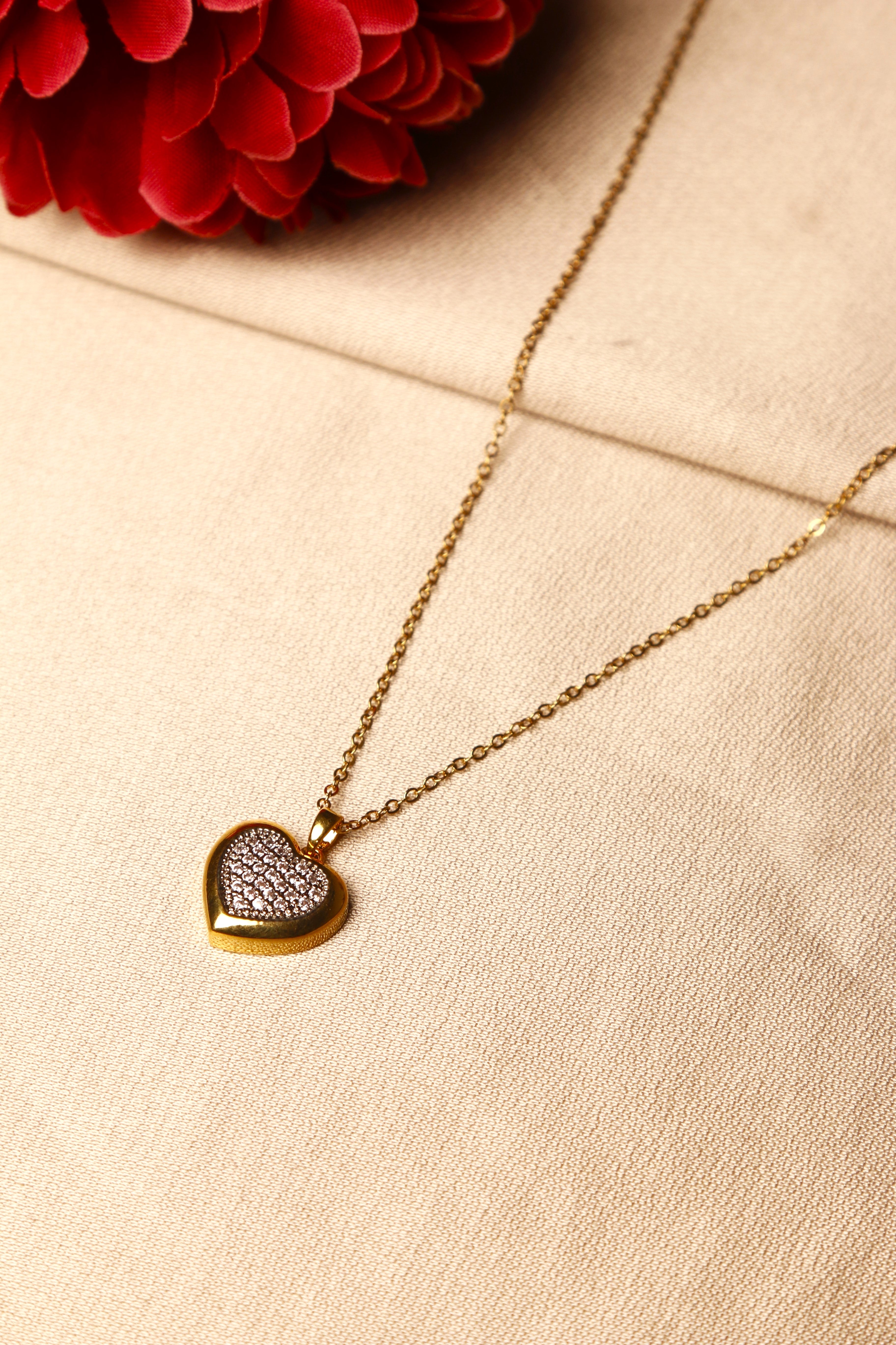 A gold heart-shaped pendant necklace with embedded diamonds.