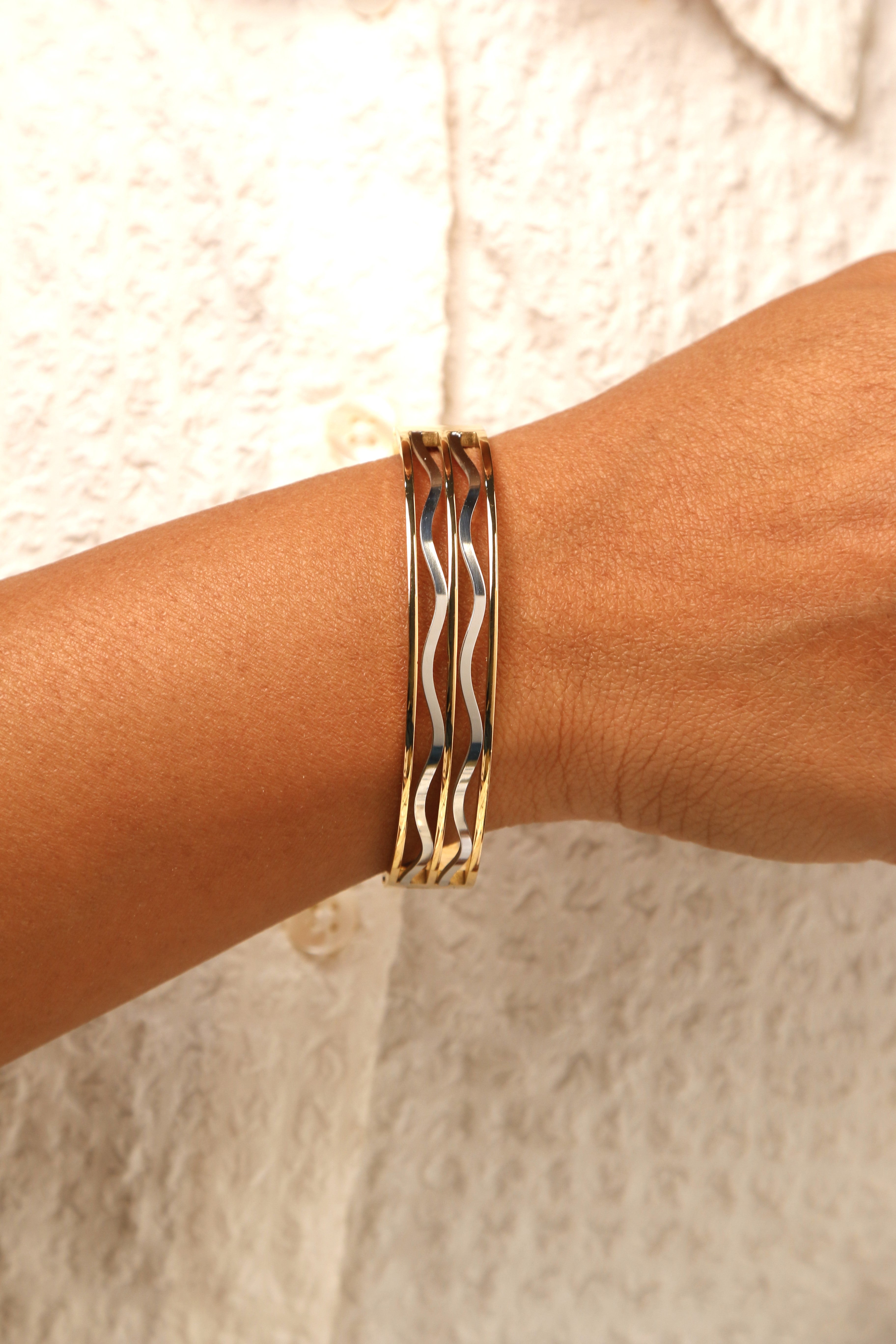Black wave-pattern hinged bracelet with gold-tone finish.