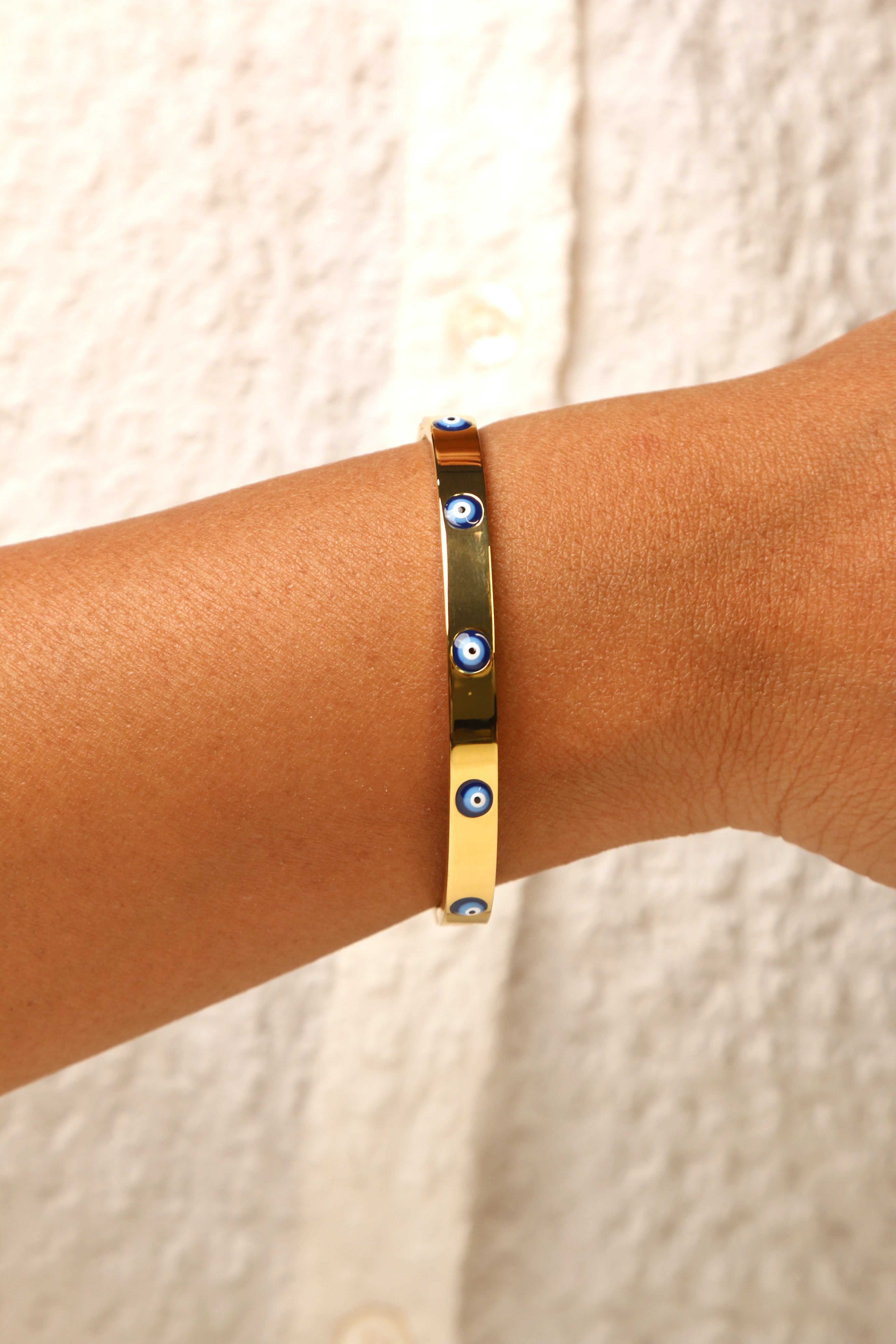 Gold-tone evil eye bracelet with a modern glow effect.