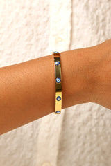 Gold-tone evil eye bracelet with a modern glow effect.