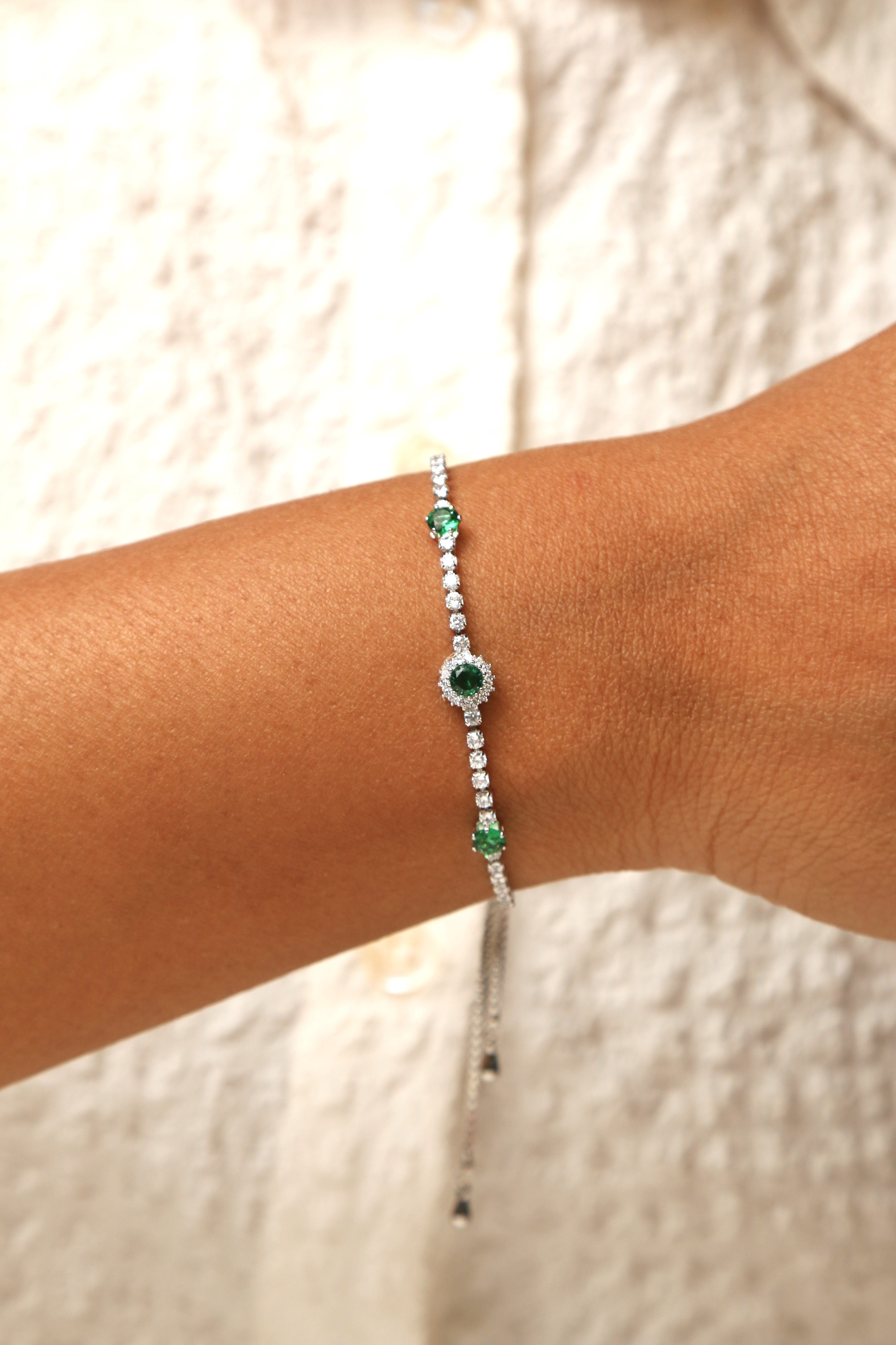 Emerald and white stone tennis bracelet with adjustable fit.