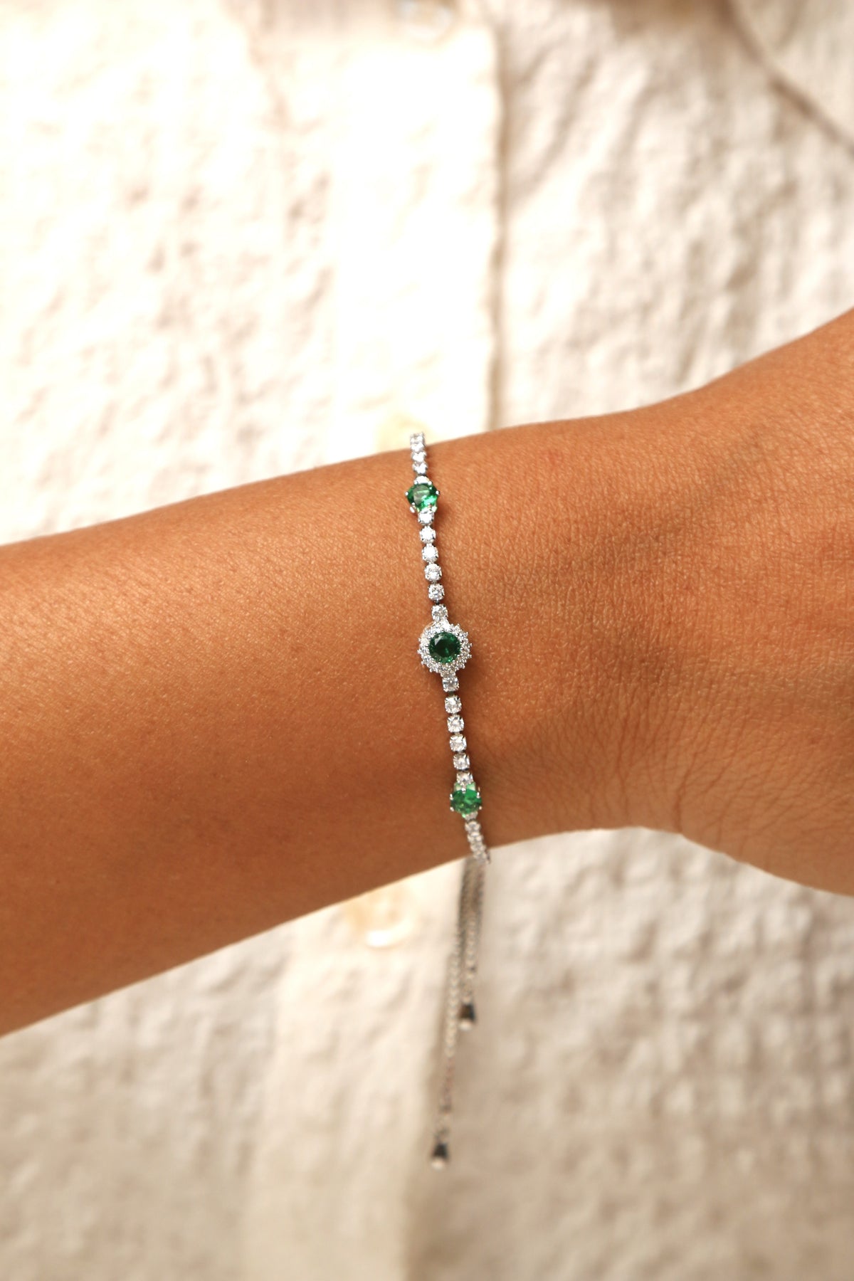 Emerald and white stone tennis bracelet with adjustable fit.
