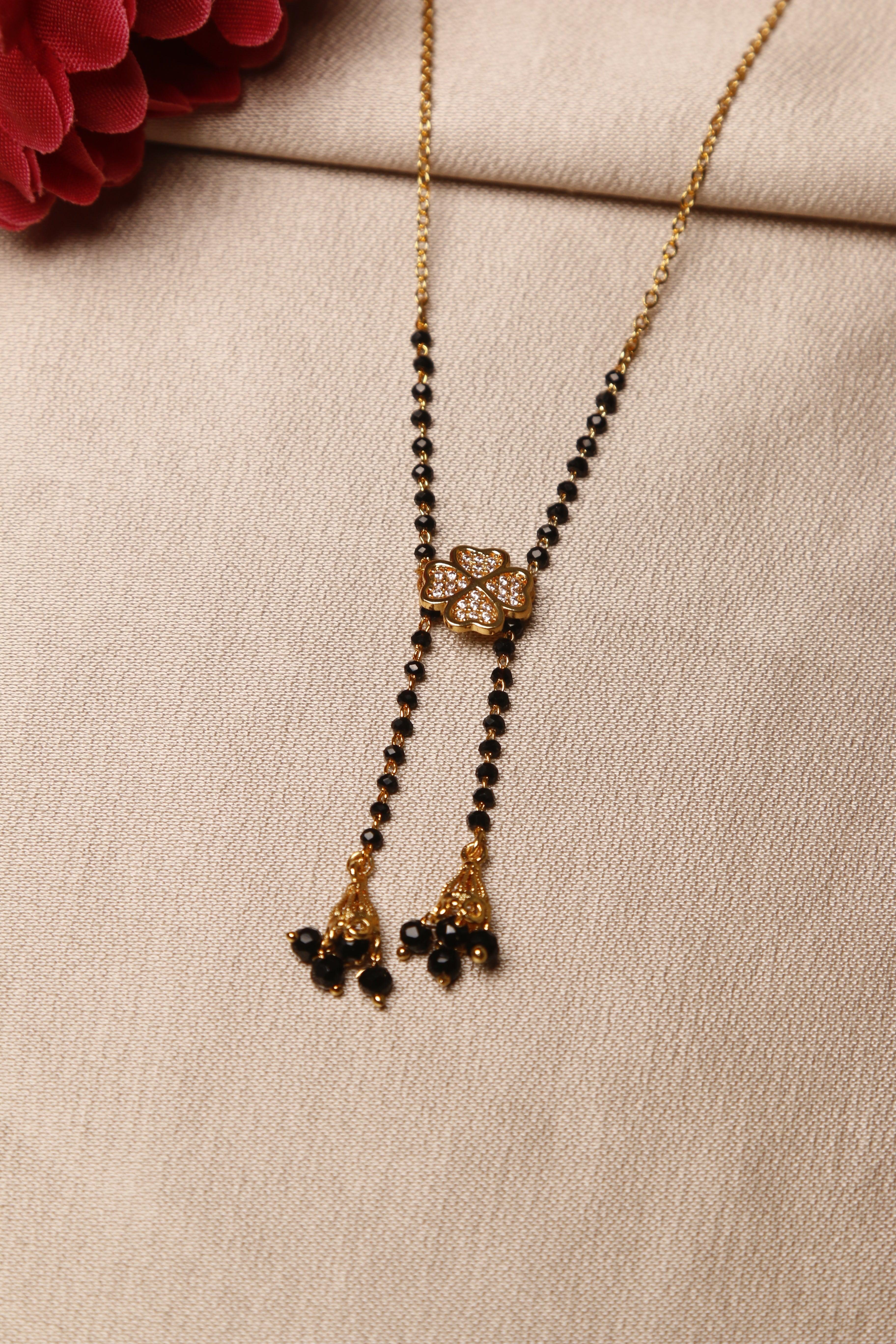 mangalsutra with a diamond-studded flower design and black beads on a golden chain, featuring hanging gold and black bead tassels.