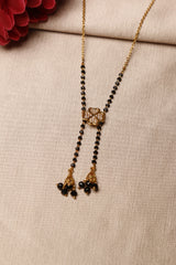 mangalsutra with a diamond-studded flower design and black beads on a golden chain, featuring hanging gold and black bead tassels.