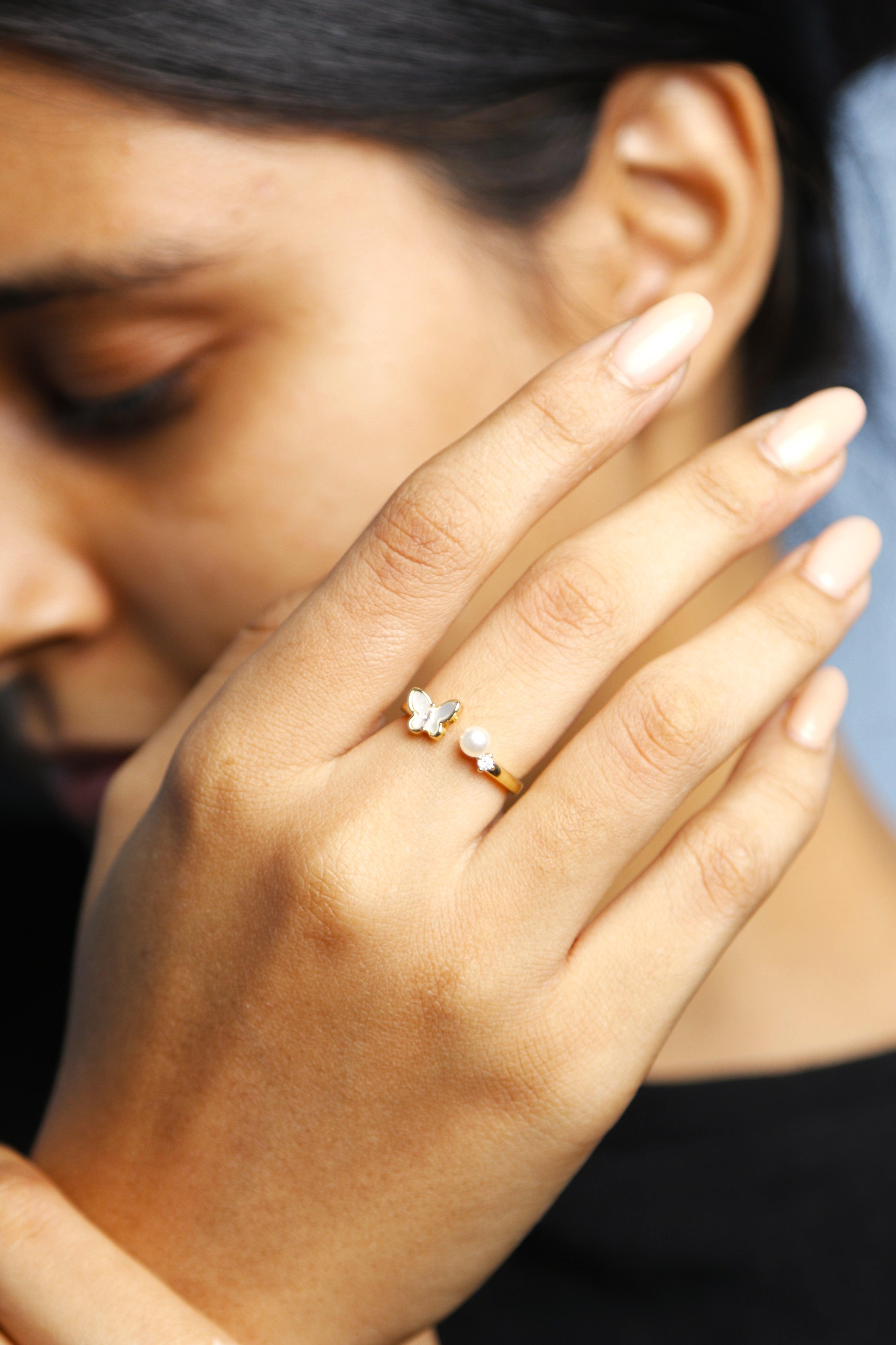 Close-up view of a butterfly ring with a pearl on a hand.