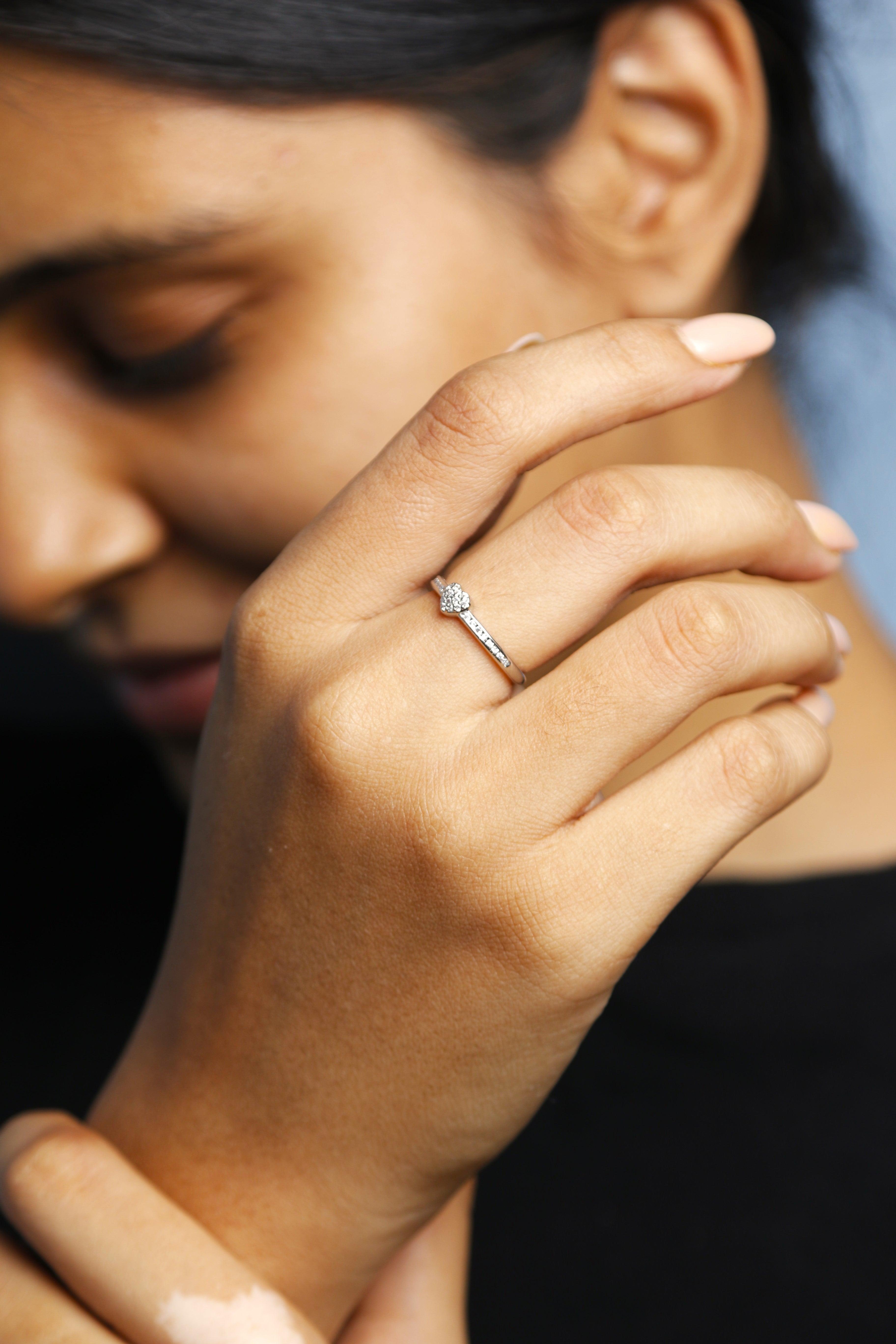 Close-up view of a heart ring with diamond detailing on a hand.