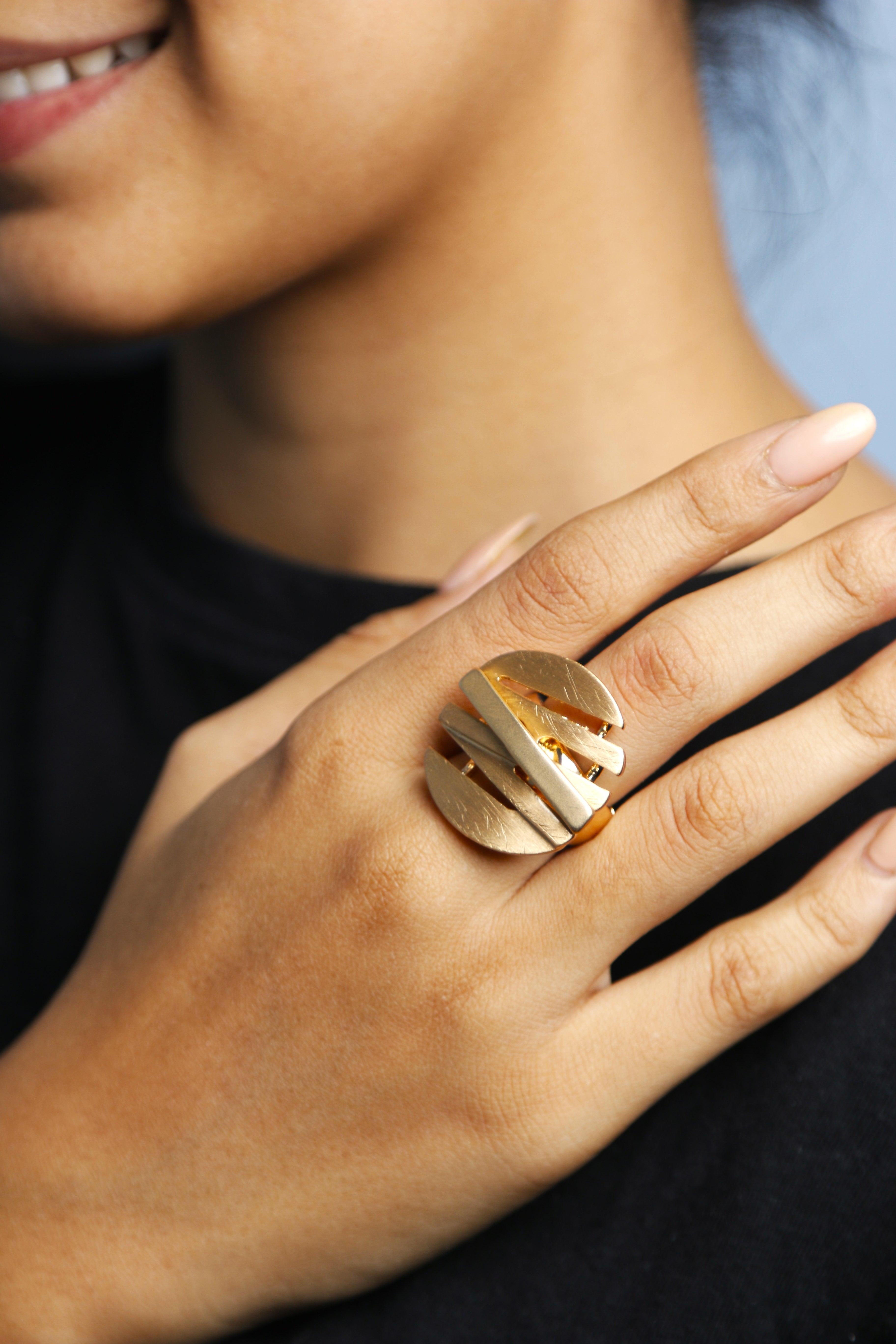 Close-up of a modern gold ring with a textured design on a hand.