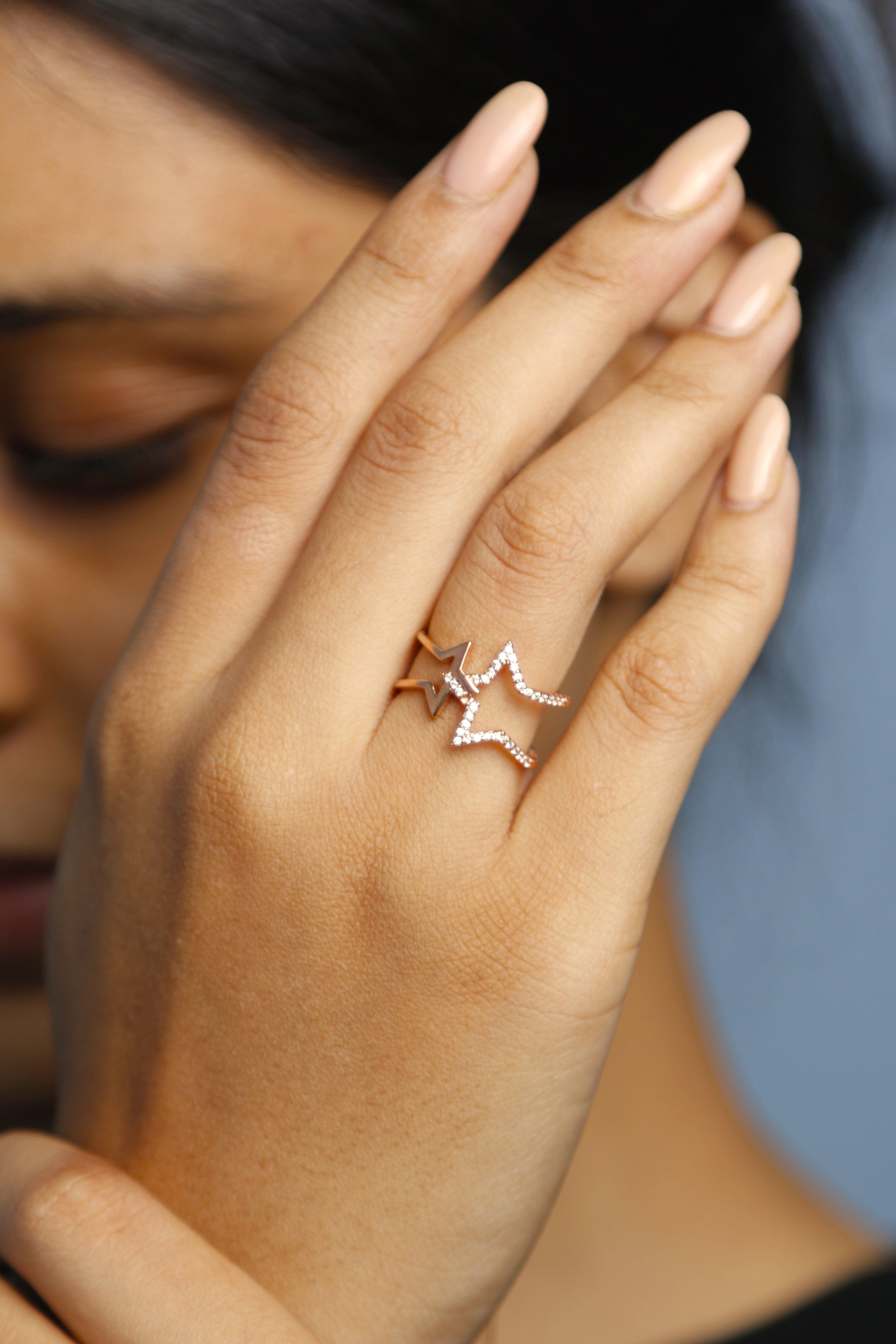 Close-up of a rose gold star ring with crystal detailing on a hand.