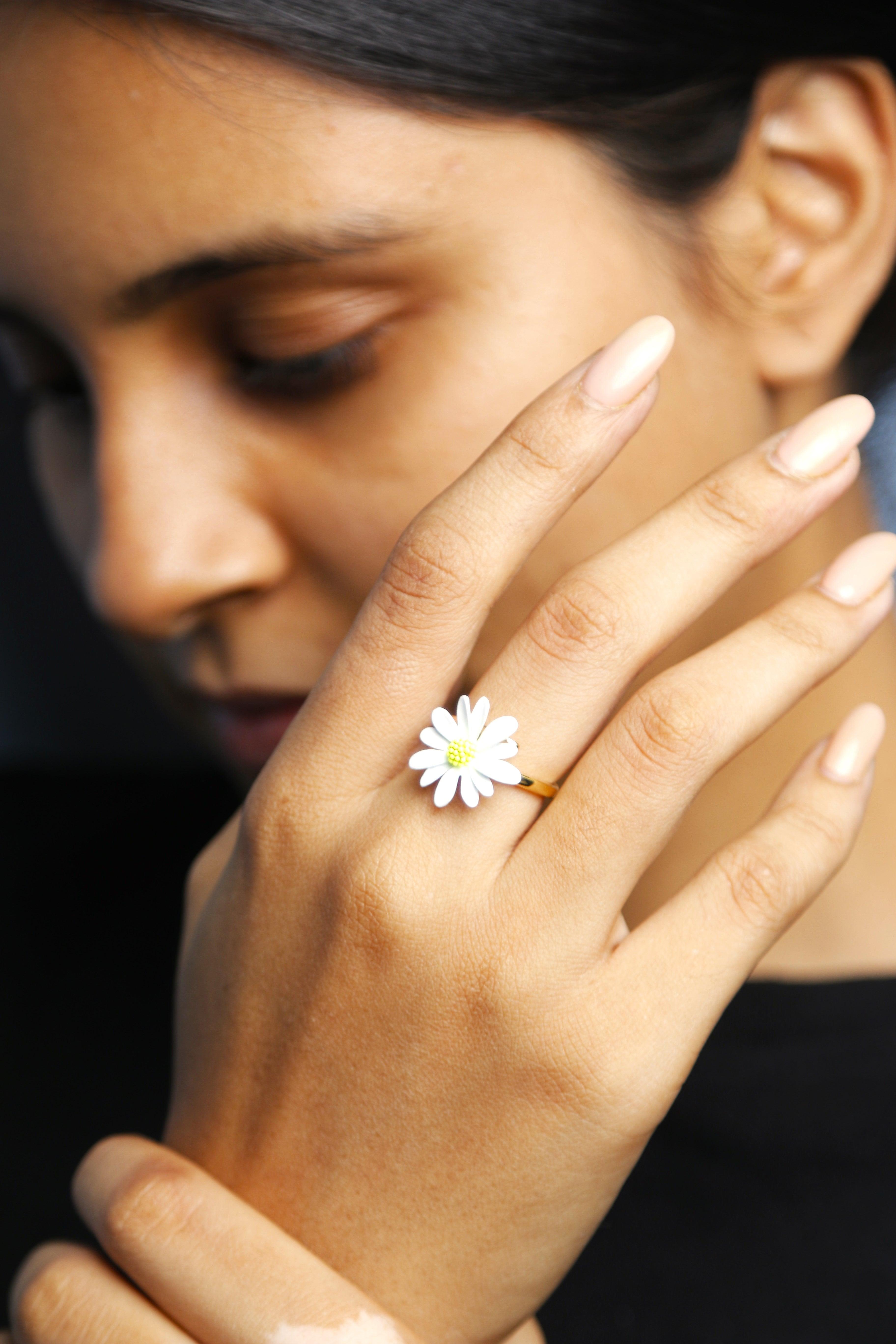 A close-up shot of a flower ring worn by a model. The gold ring.