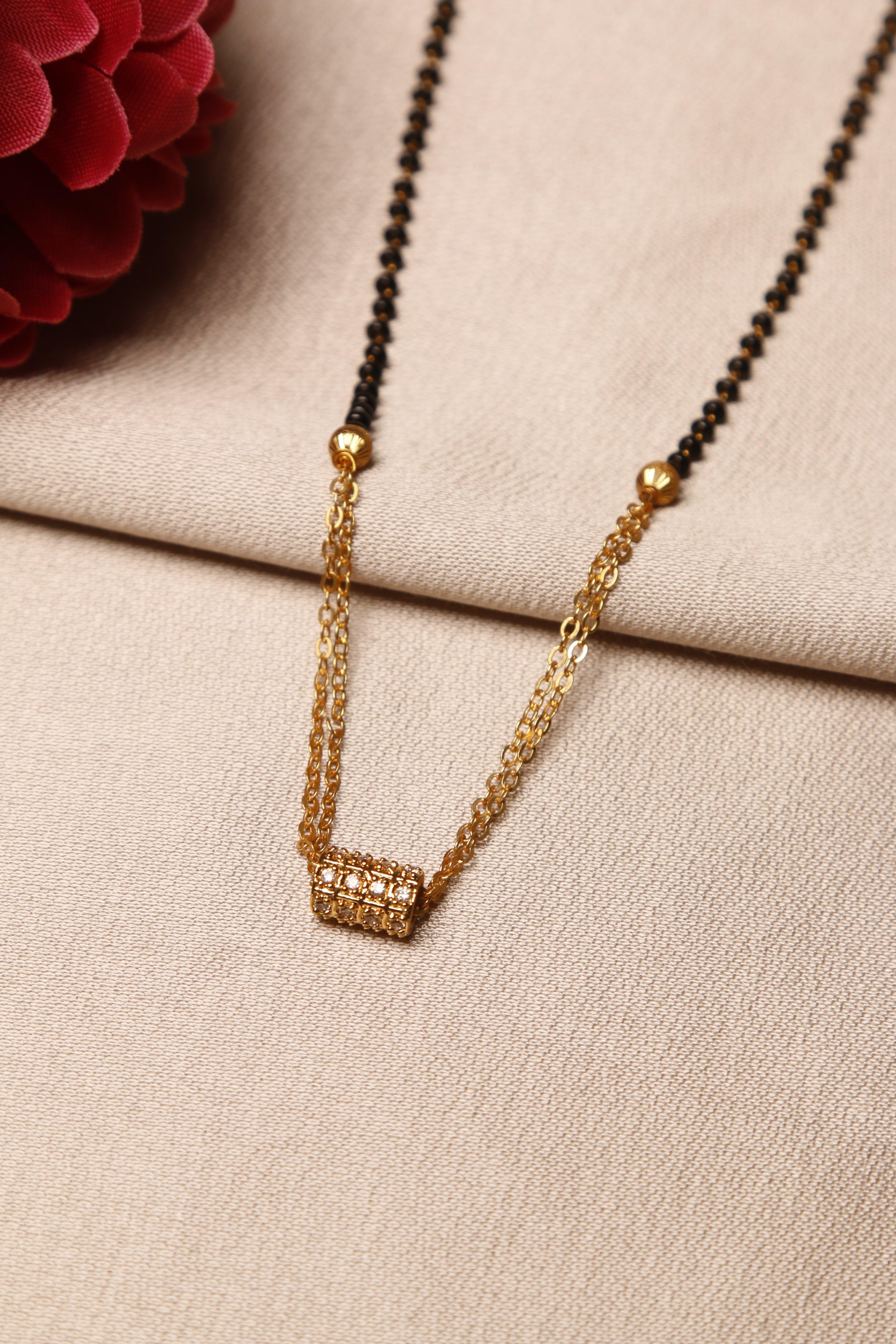 A close-up of a diamond-studded gold mangalsutra with a chain featuring black beads and a small decorative pendant.