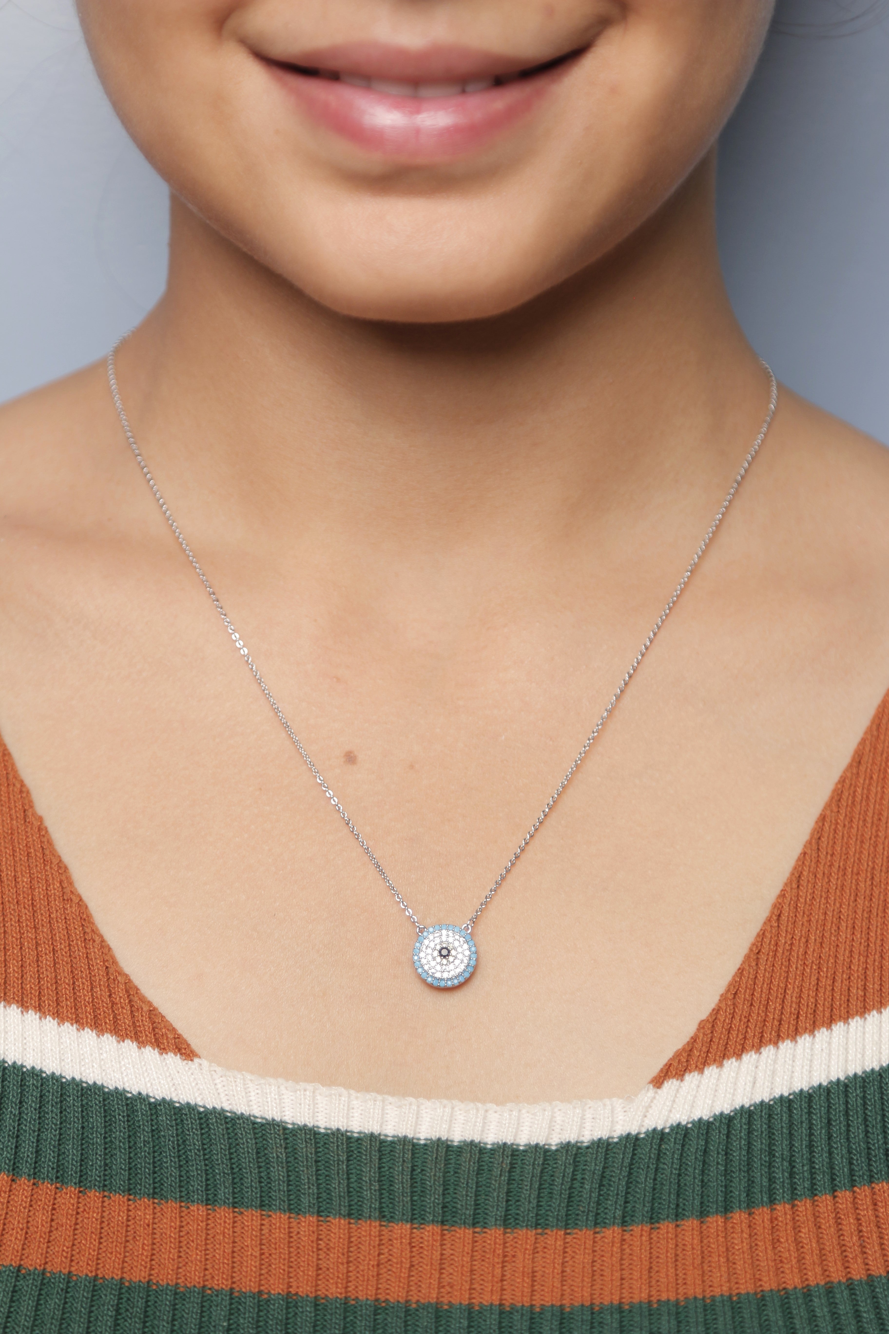Silver diamond necklace with a circular design, worn by a woman.