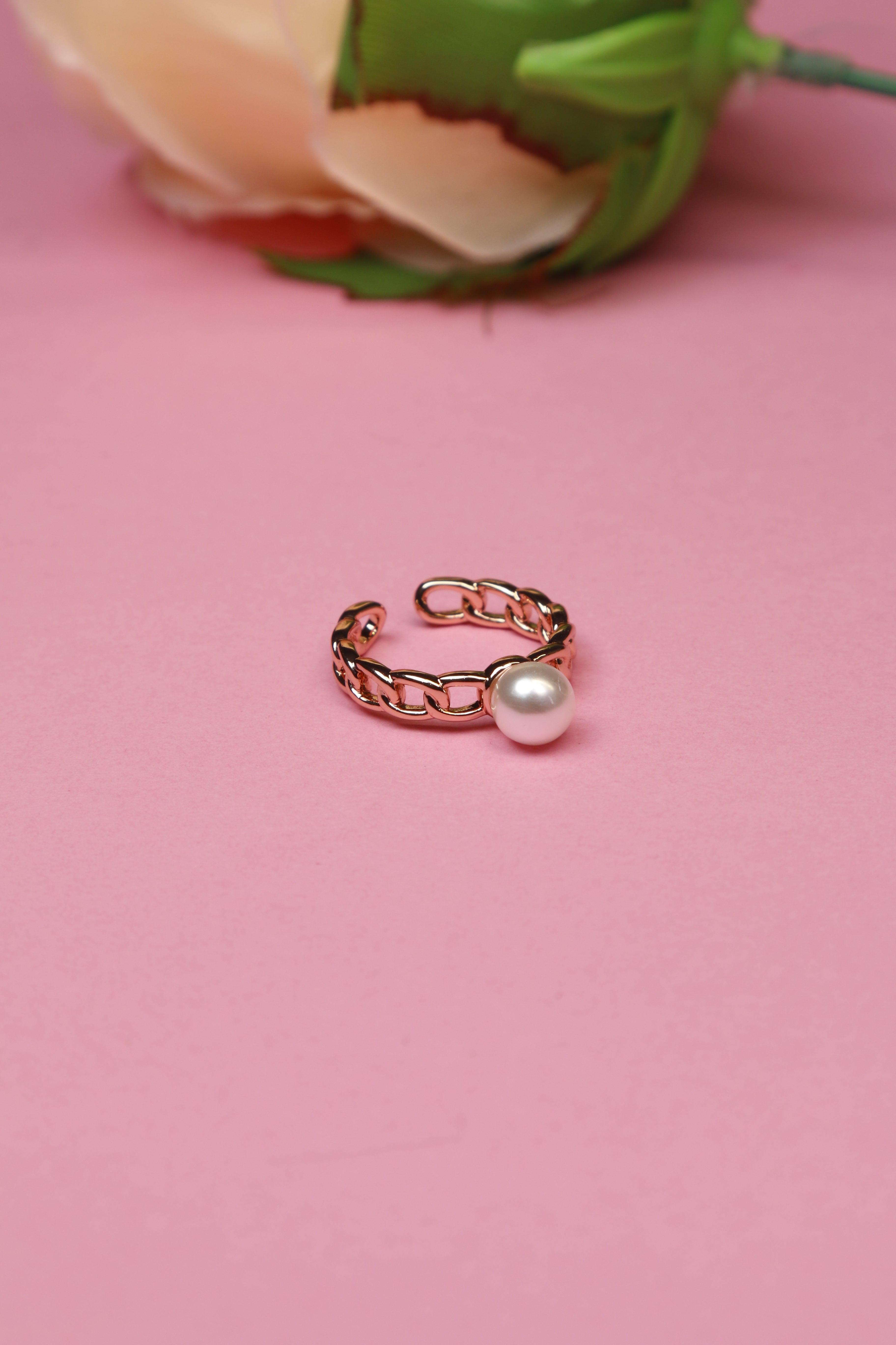 A beautiful rose gold chain pearl ring placed on a pink background.