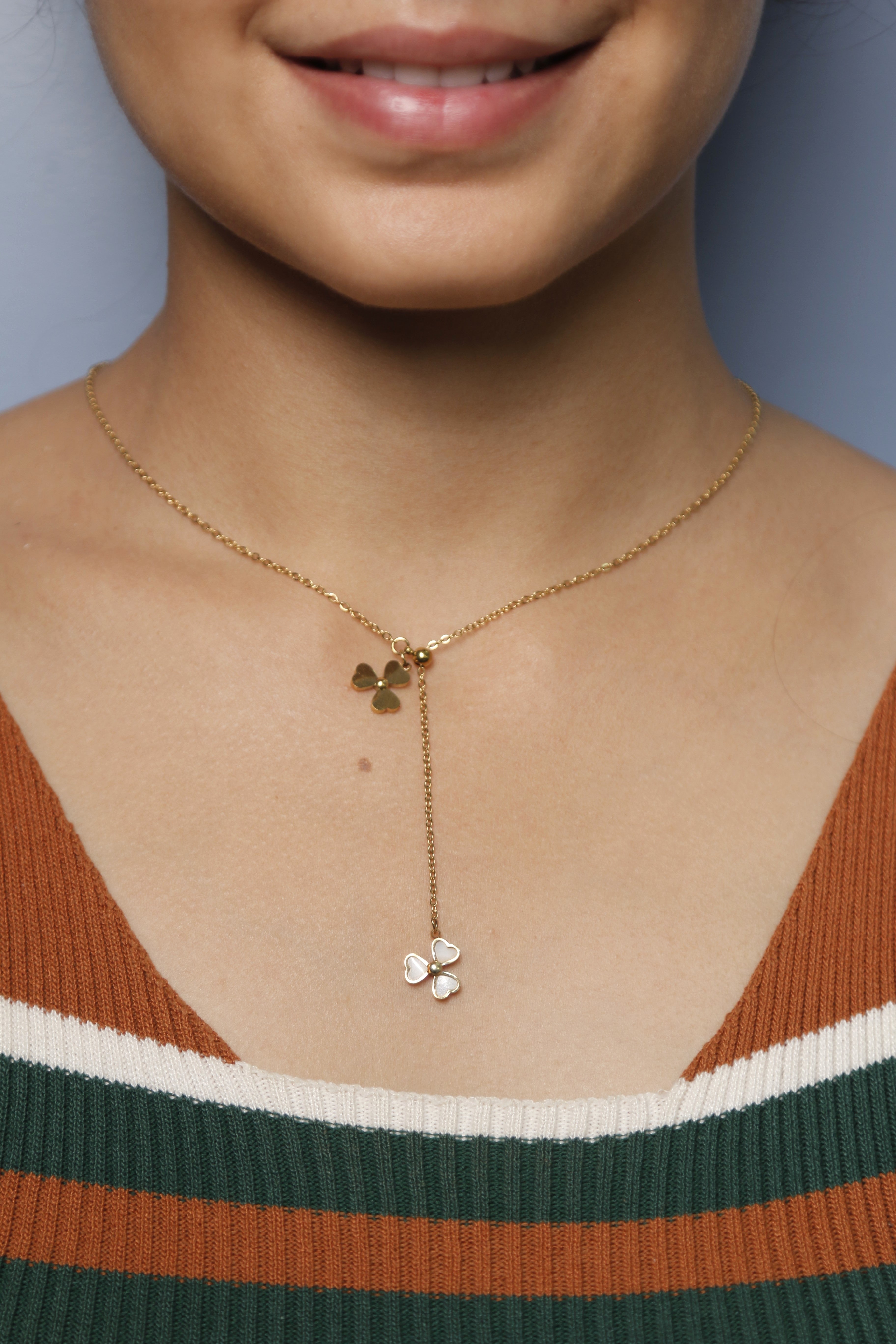 A woman wearing a Dual charming gold Flower-shaped necklace with delicate gold detailing.