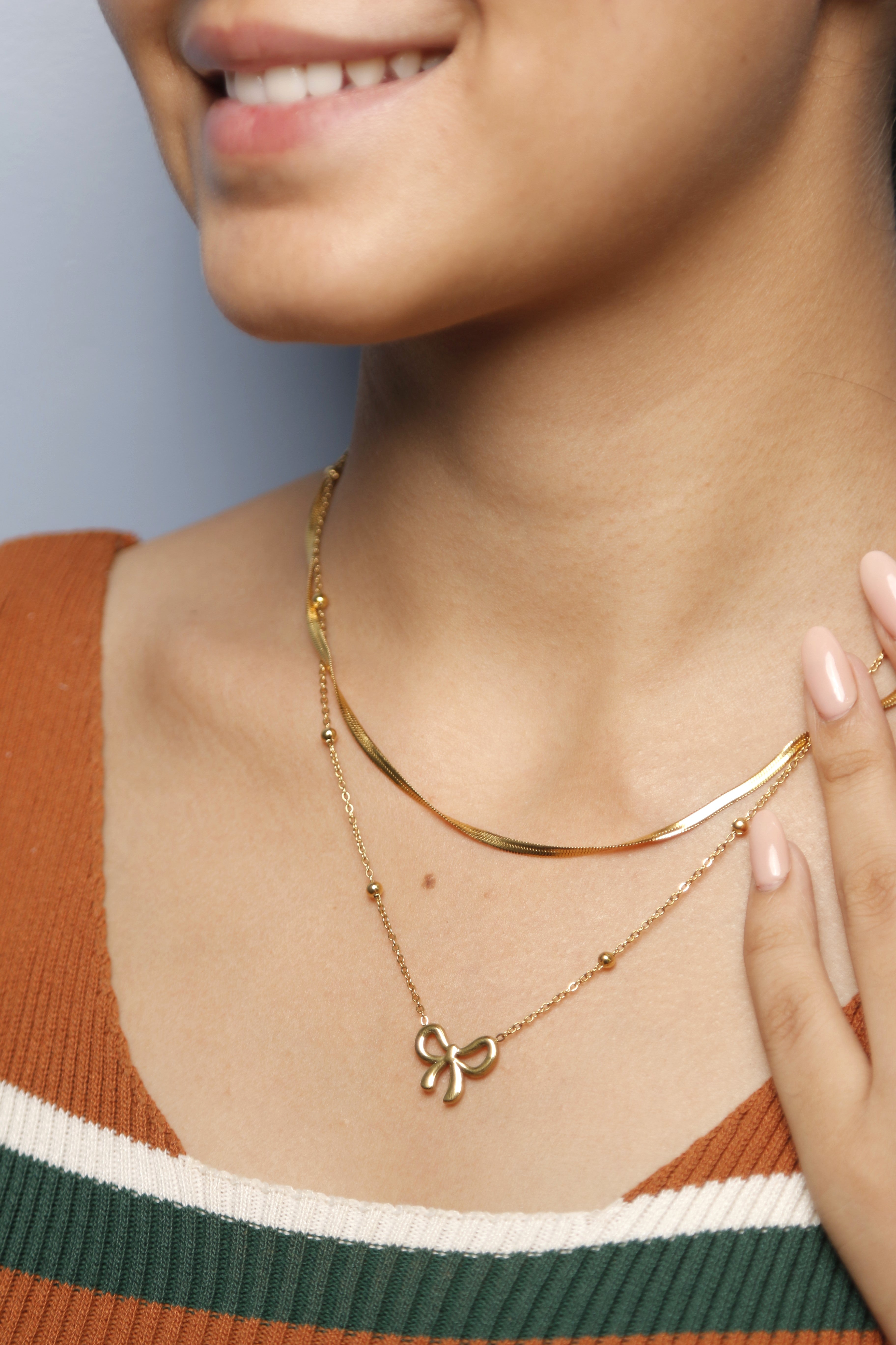Close-up image of a woman wearing a gold bow necklace.