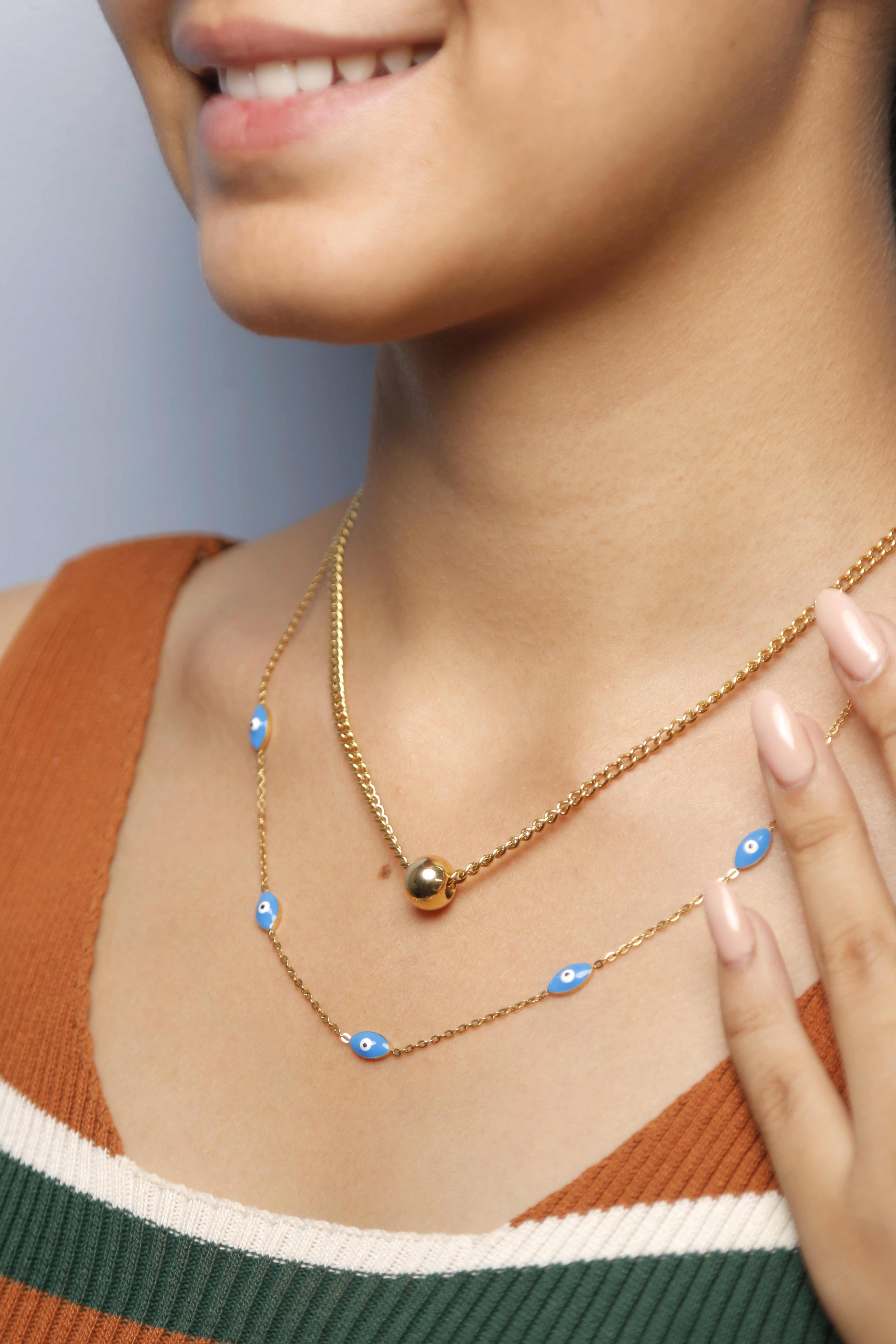 Close-up of a woman wearing a gold necklace with blue eye-shaped pendants.