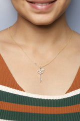A woman wearing a delicate gold key-shaped necklace adorned with sparkling diamonds