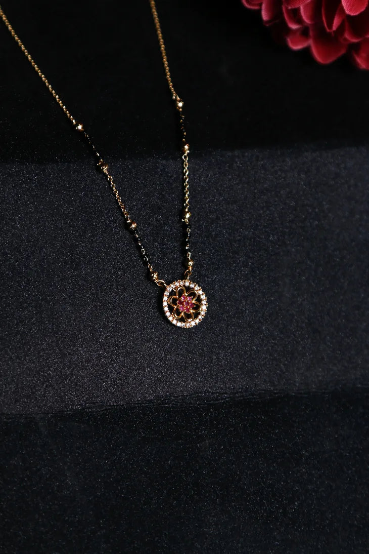 Gold mangalsutra with floral pendant and ruby red center stone