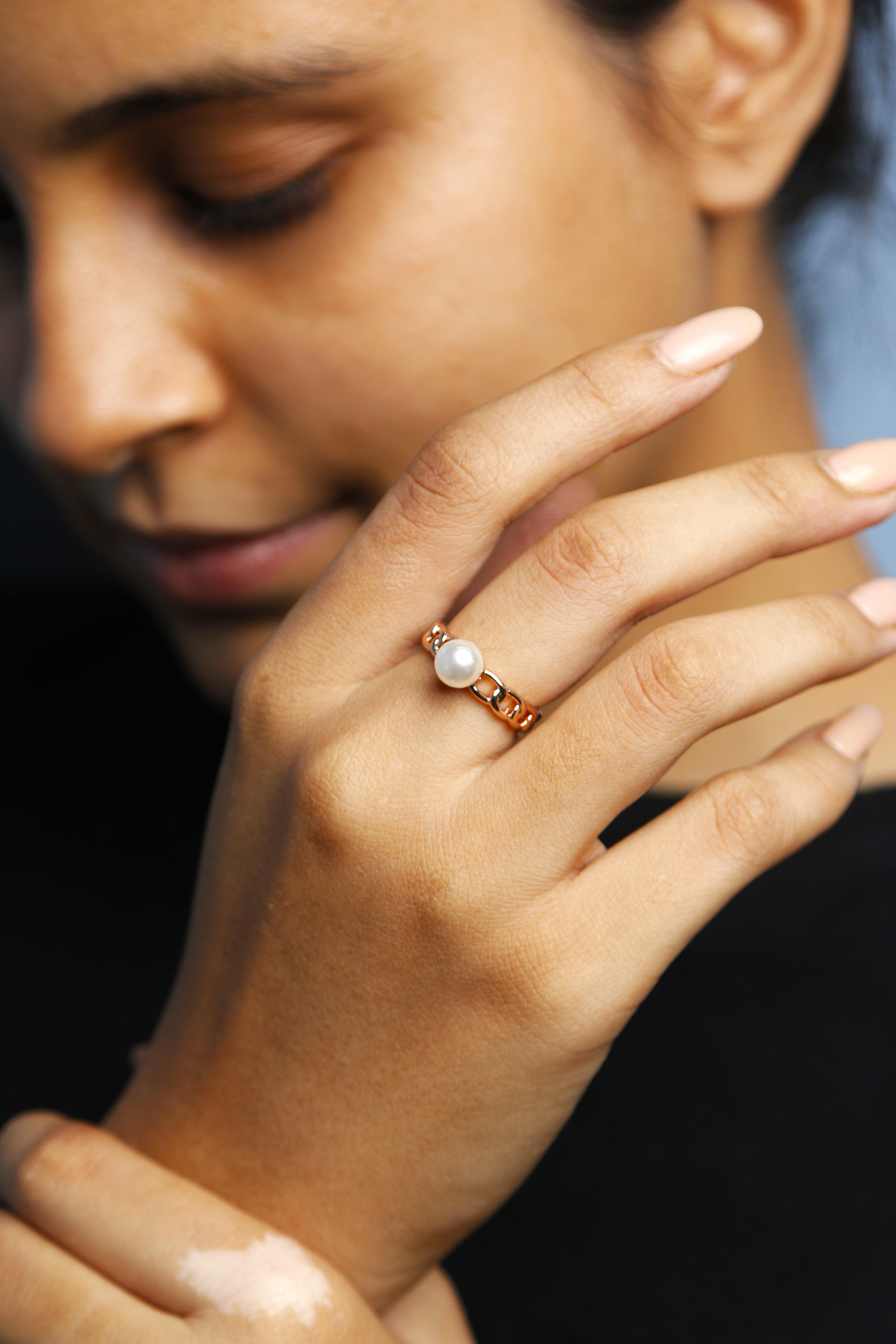 Close-up shot of a woman wearing a rose gold chain pearl ring.
