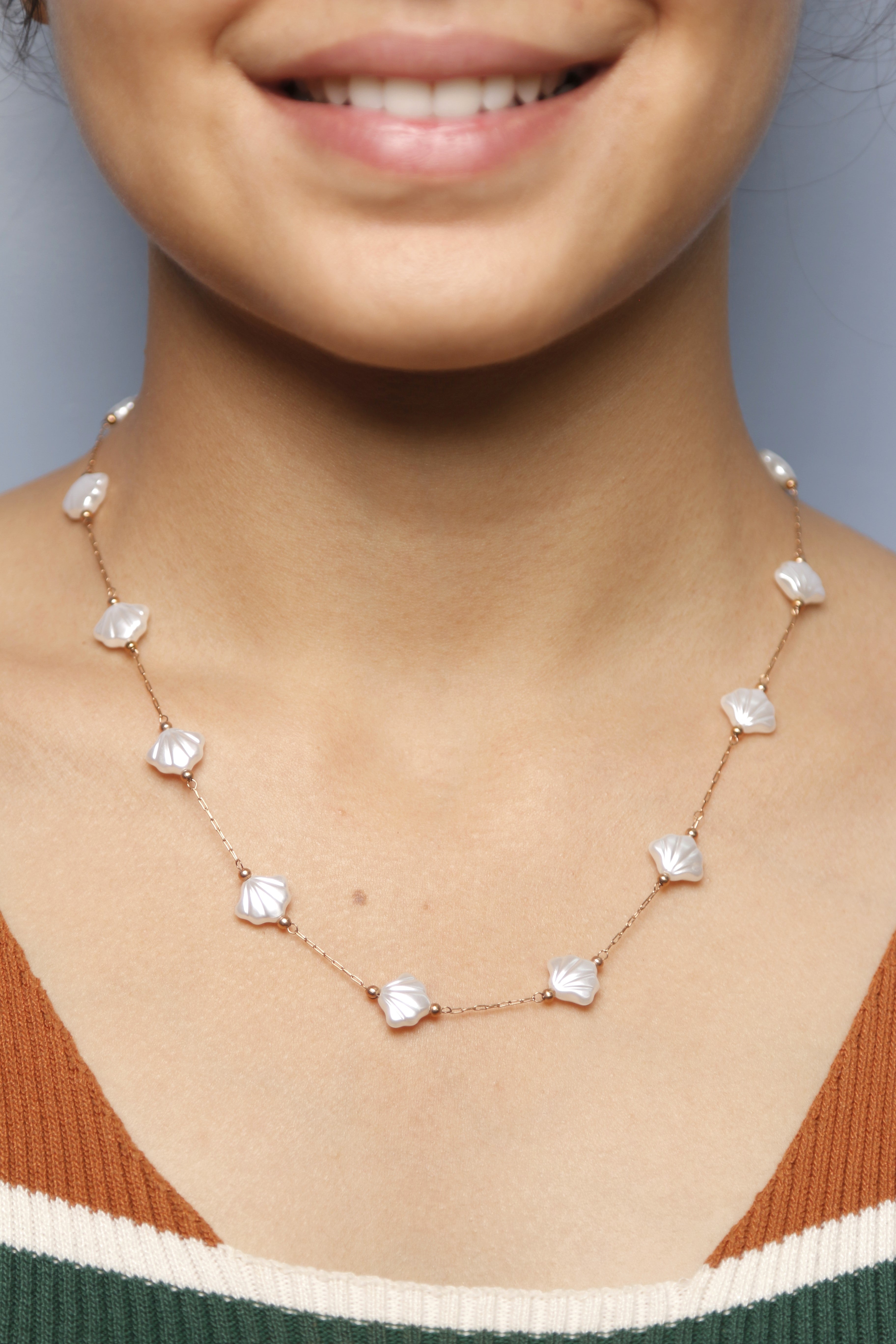 Close-up image of a woman wearing a pearl shell necklace.