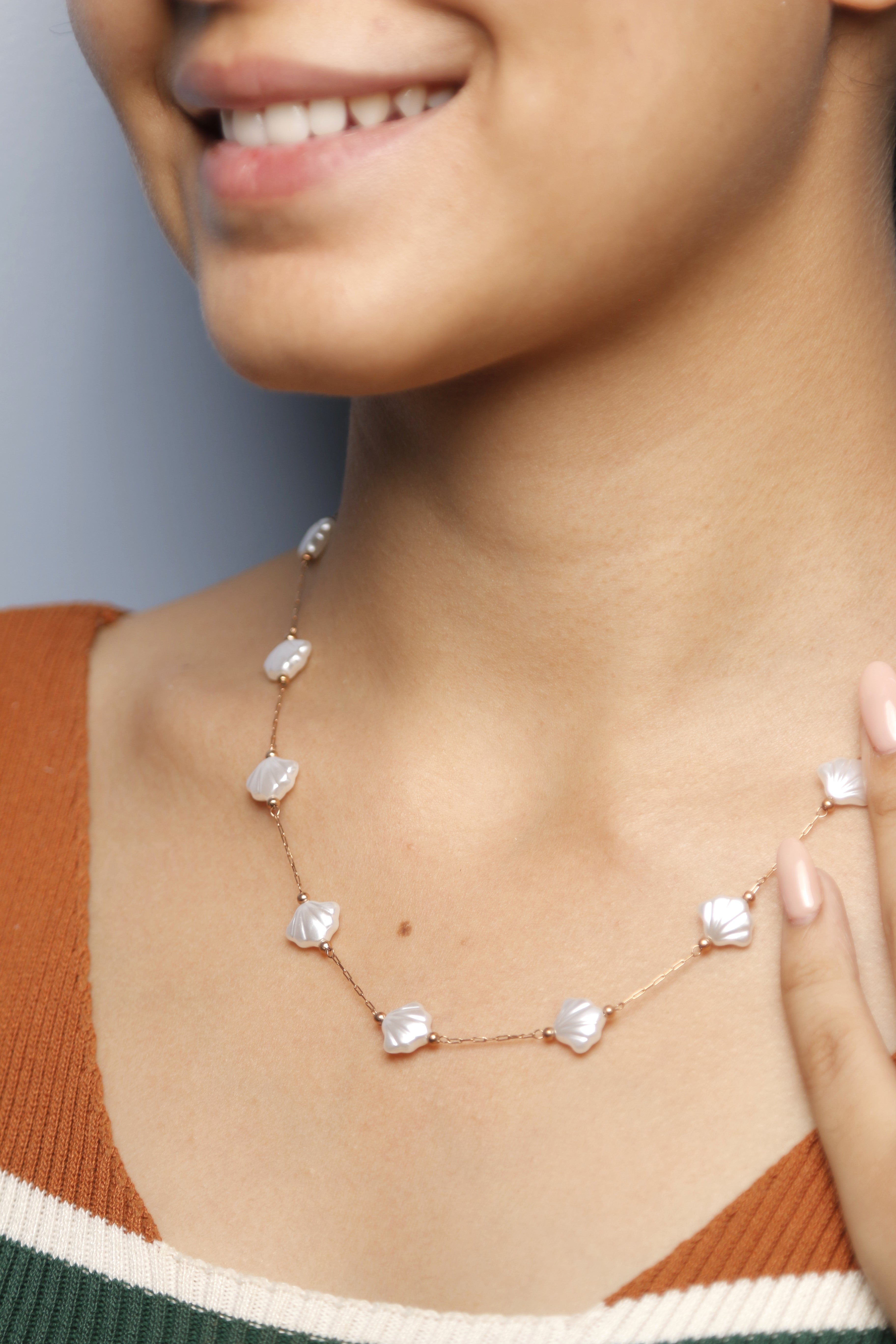 Close-up image of a woman wearing a pearl shell necklace.