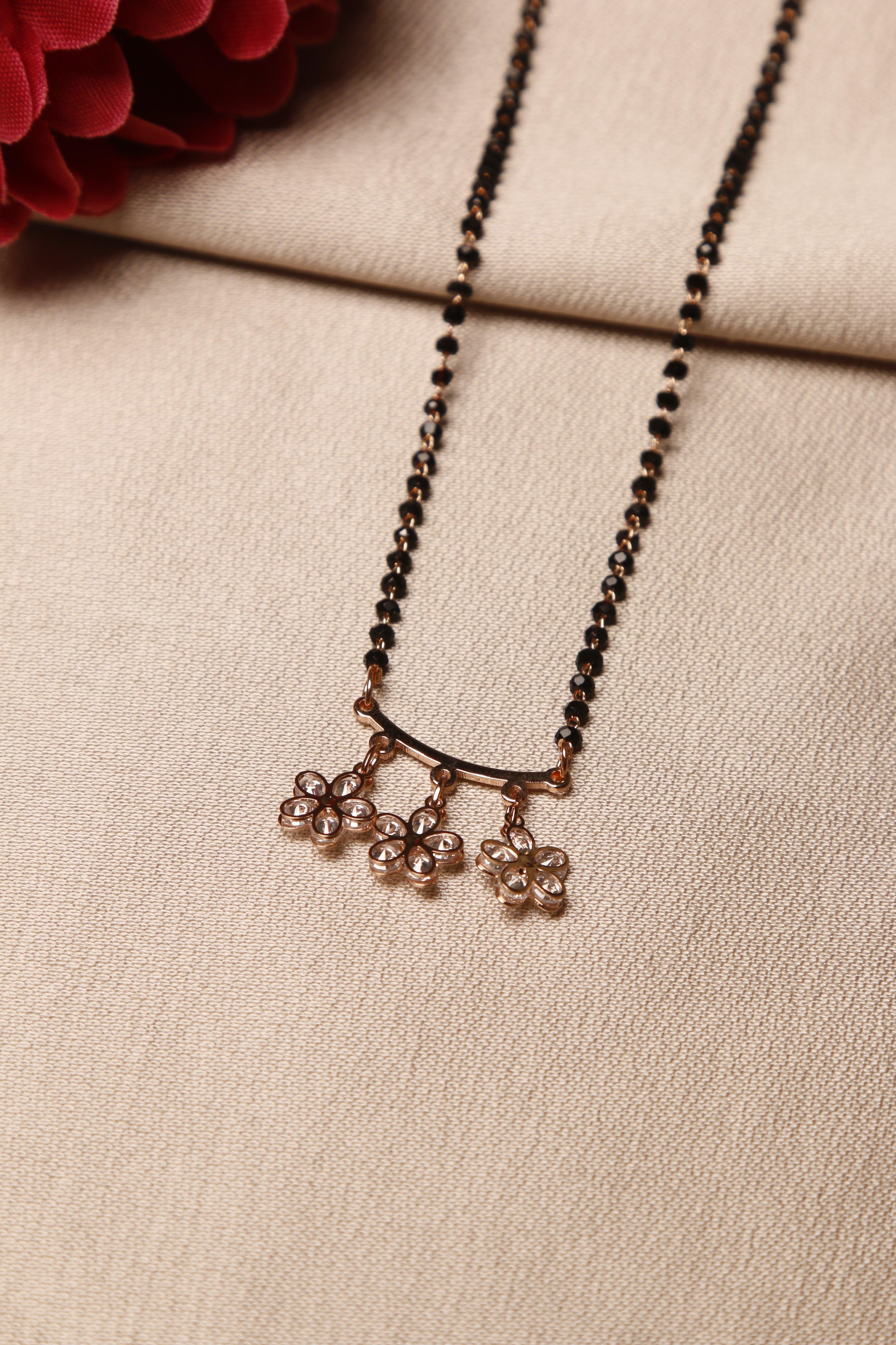 A close-up of a flower-shaped diamond mangalsutra on a woman, adorned with black beads and a simple, elegant design.