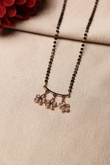 A close-up of a flower-shaped diamond mangalsutra on a woman, adorned with black beads and a simple, elegant design.