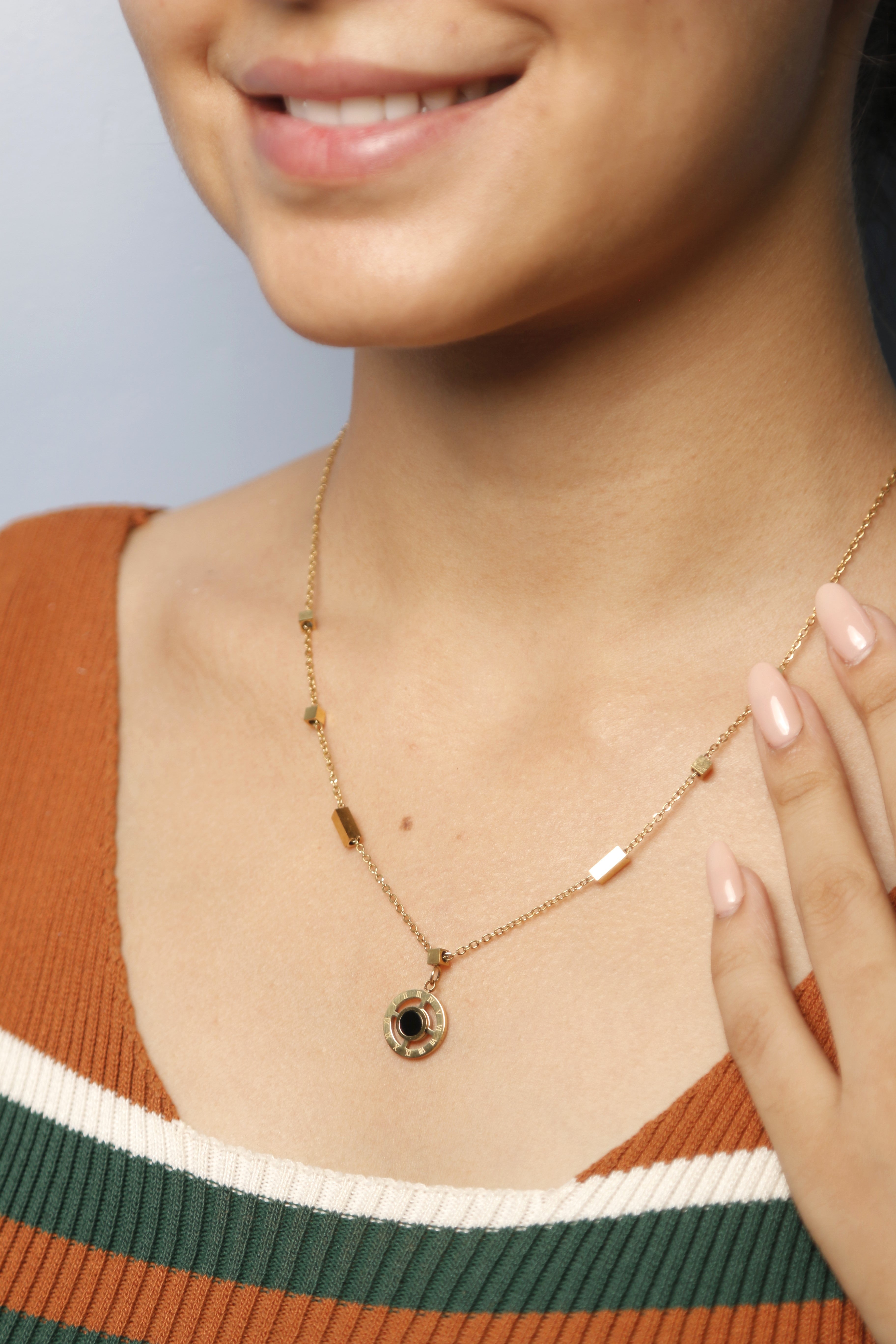 A woman delicately adjusting her gold and pearl necklace.