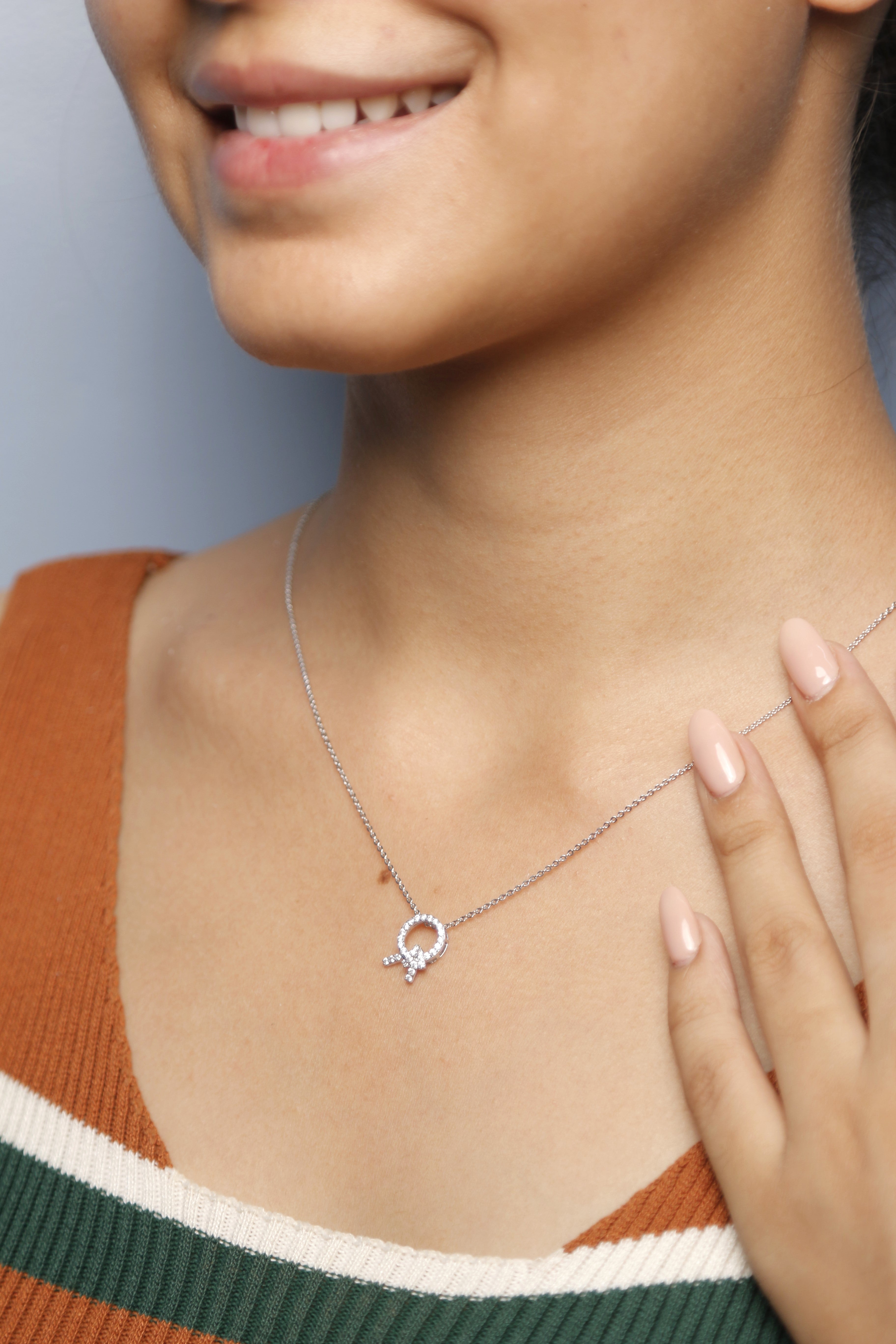 A woman gently touching her silver necklace adorned with a diamond pendant.