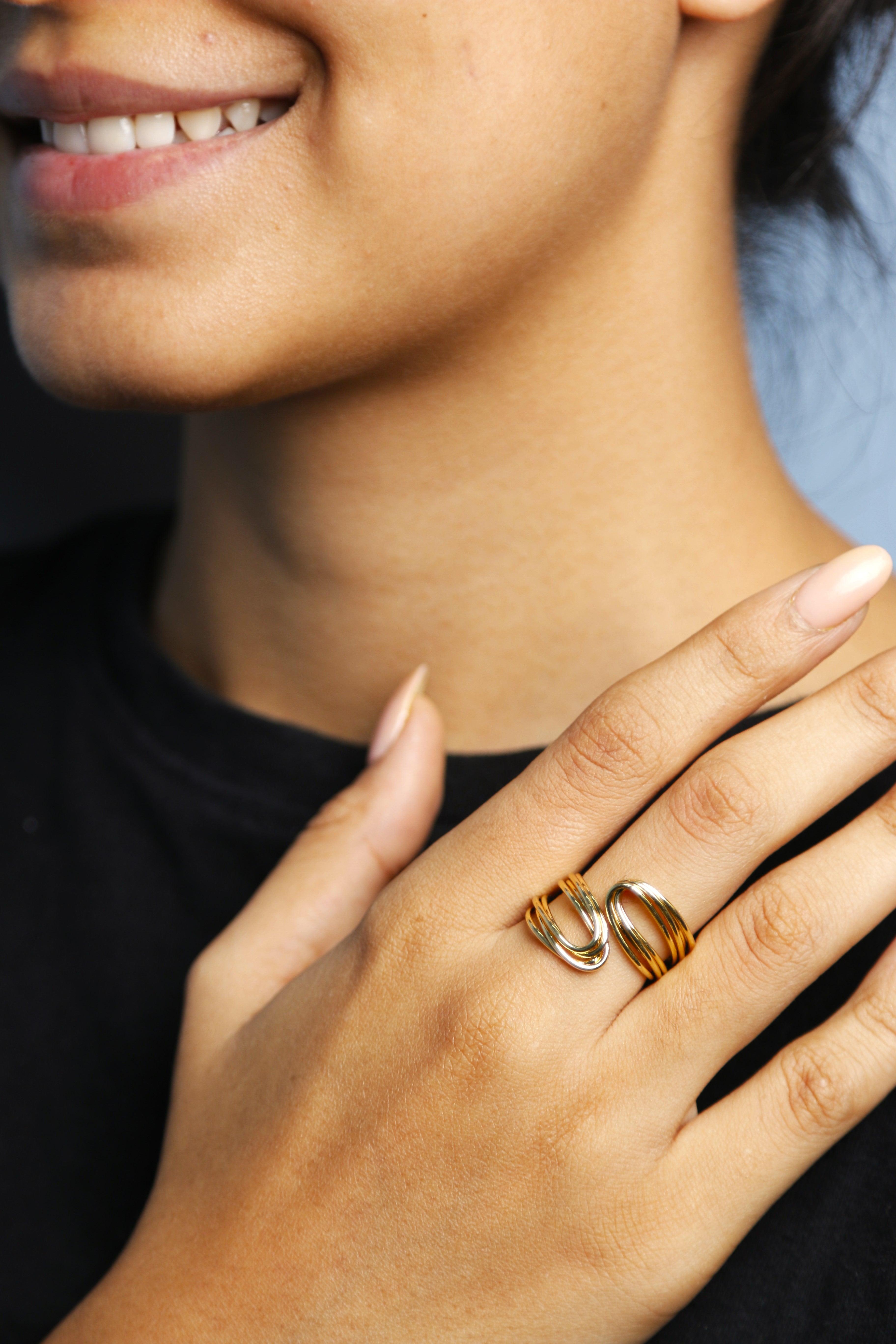 Woman wearing a gold ring with flowing design on her finger.