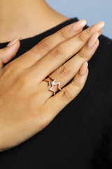 Woman wearing a rose gold star ring with crystal embellishments on her finger.