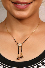 Close-up of a woman wearing a stylish black-beaded mangalsutra with a diamond flower pendant and gold tassels.